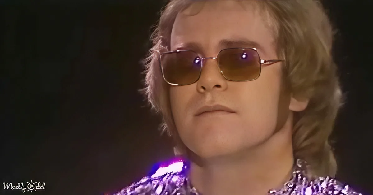 A person with blonde hair and sunglasses, wearing a sparkly outfit, is the main subject.