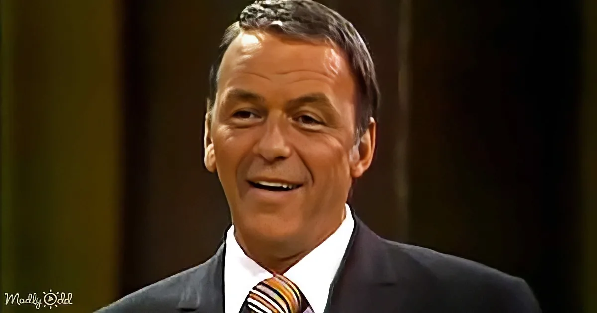 A man in a suit and striped tie smiles warmly, with a dark background.