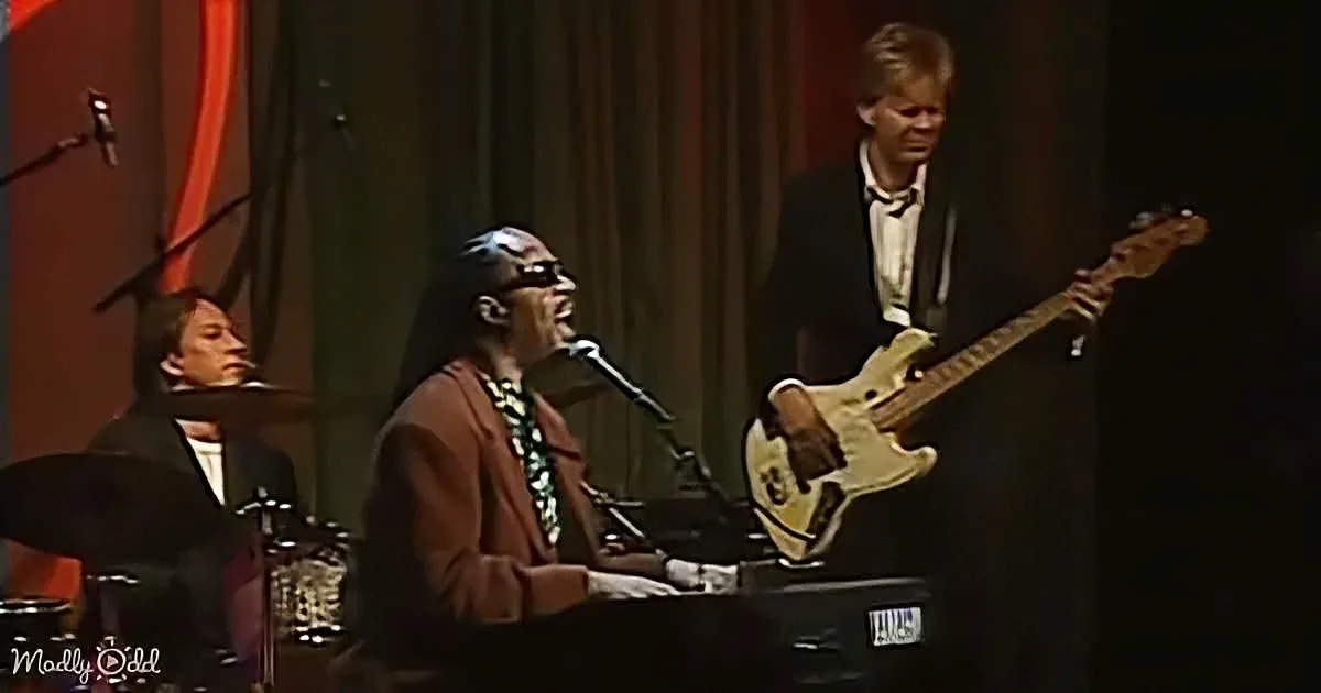 A man in a brown suit plays piano while another in a black suit plays bass guitar.