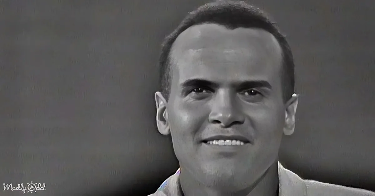 A man with short hair and a light-colored shirt is smiling in a grayscale image.