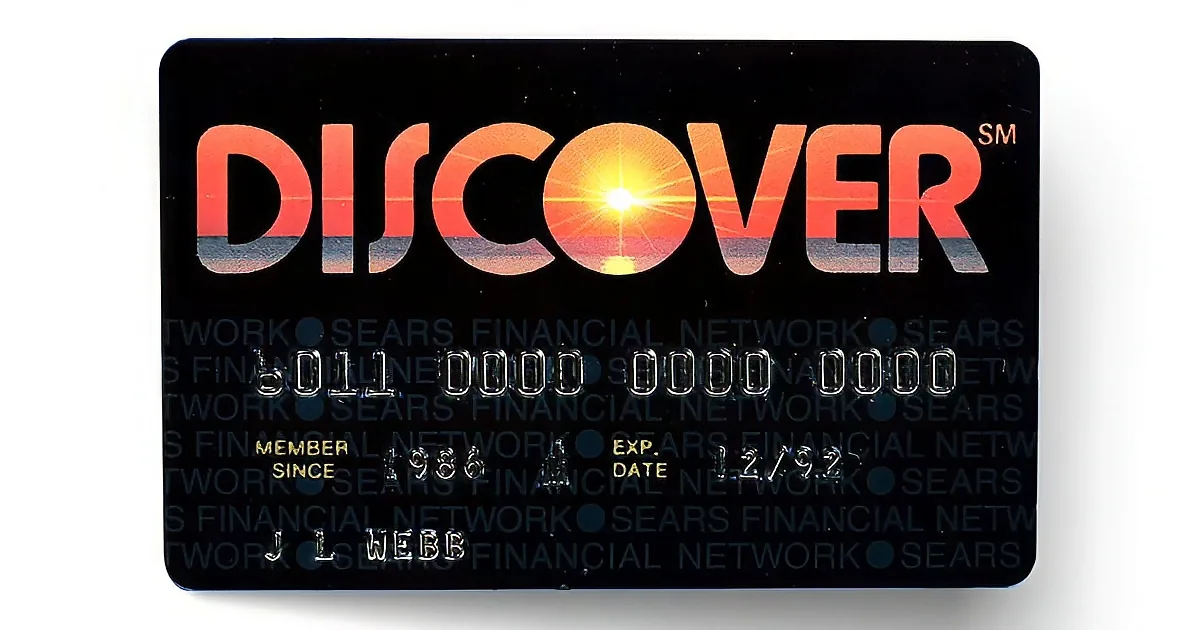 A Discover credit card with a sunset design, showing the number 6011, expiration date 12/23, and member since 1986.