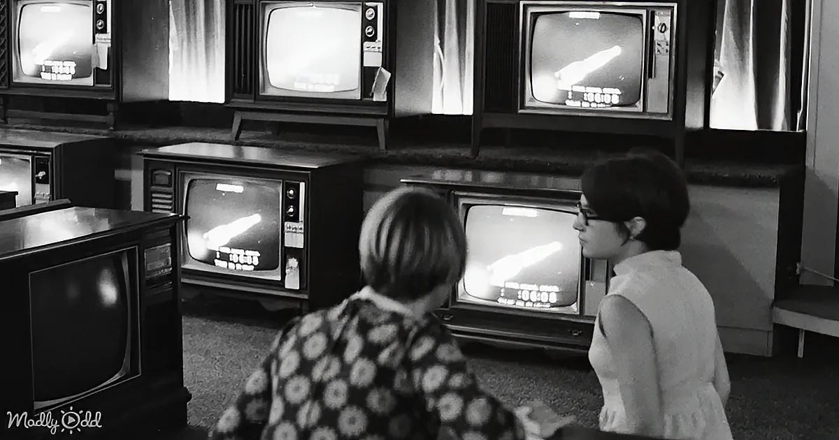 Two women are playing a video game on vintage televisions in a retro setting.