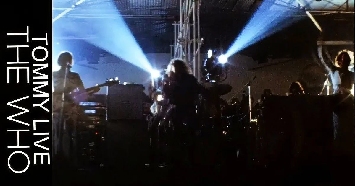 A person with curly hair sings into a microphone, surrounded by distorted, fragmented visuals.