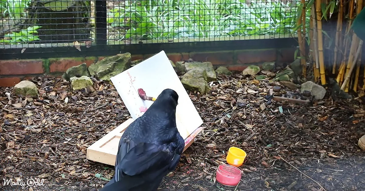 A crow perches on a canvas, seemingly painting a red flower amidst greenery.