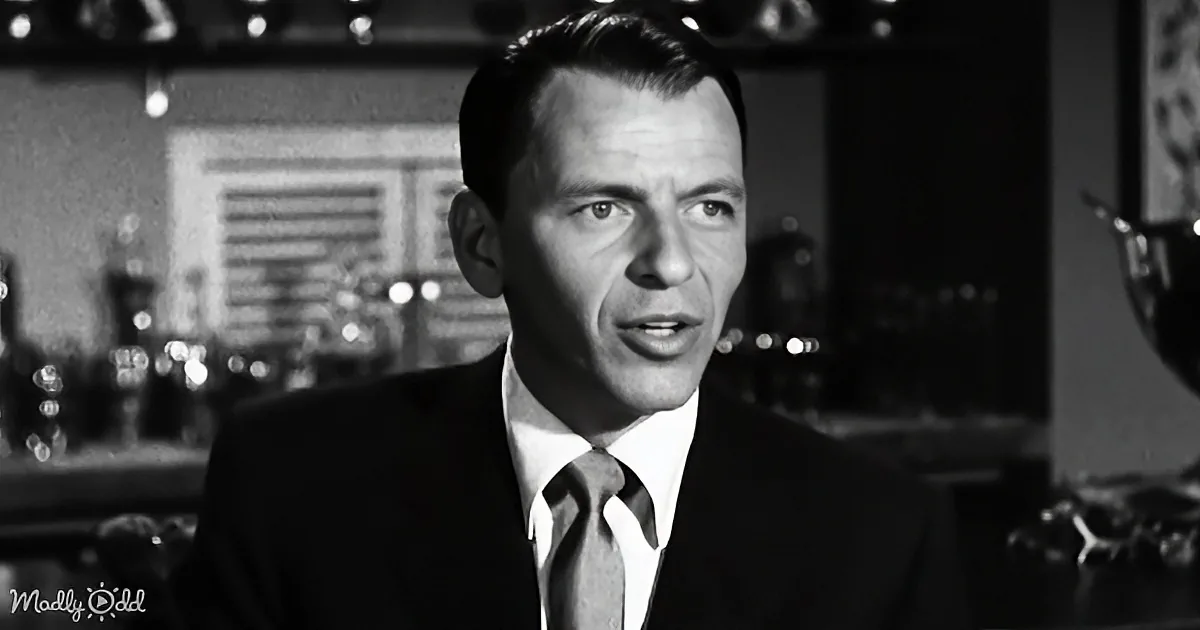A man in a suit and tie stands in a dimly lit bar, looking slightly to the side.