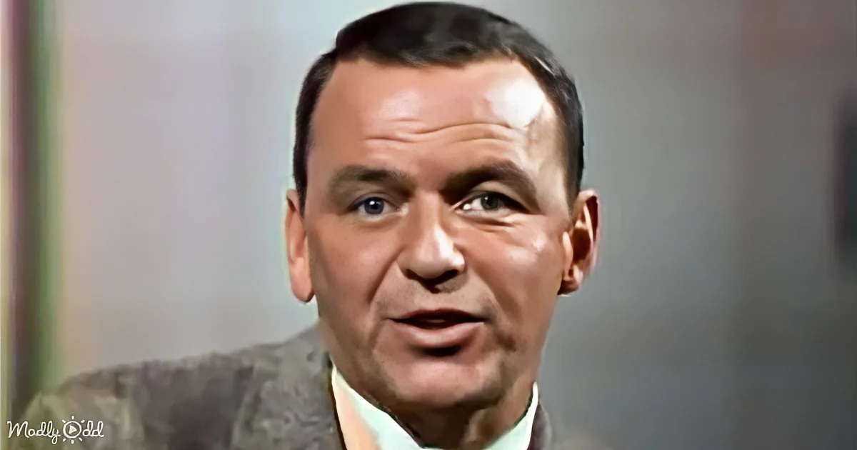 A man with short dark hair, wearing a suit and tie, is looking slightly to the side with a neutral expression.