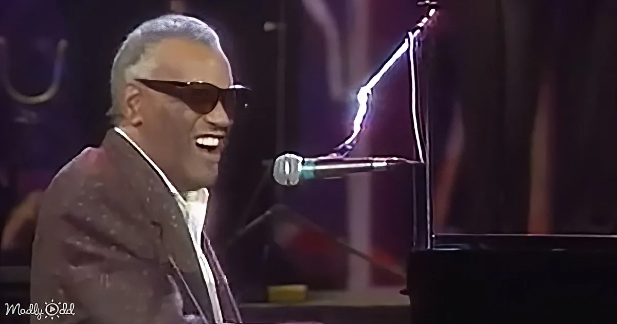 A man in sunglasses and a suit is singing and playing piano on stage.