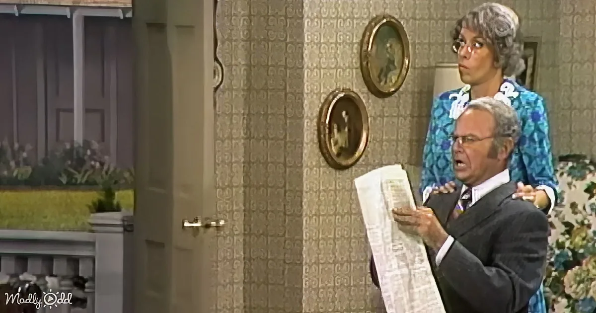 A man in a suit holds a newspaper, appearing surprised, with a woman in a floral dress behind him.