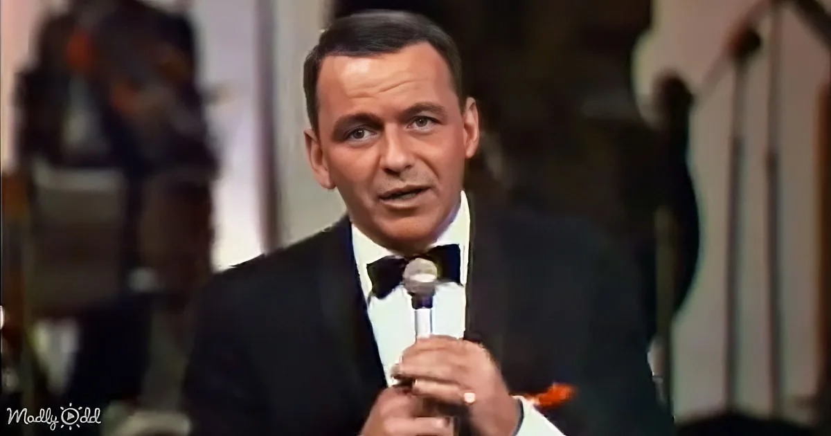 Frank Sinatra in a tuxedo holding a microphone, singing on stage.