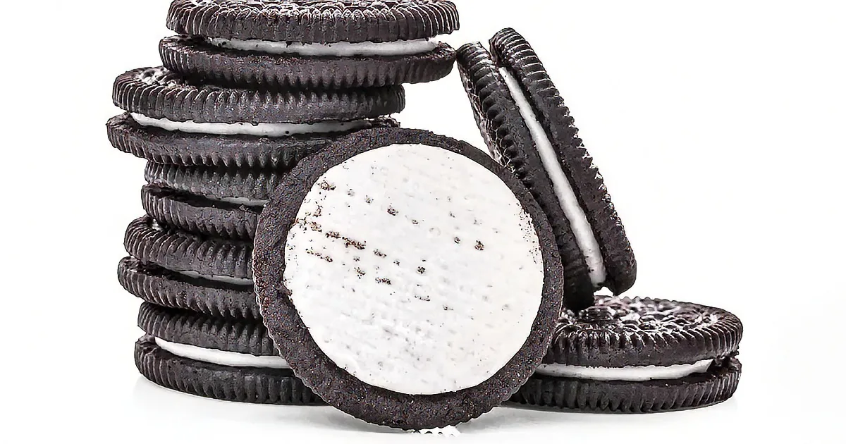 A stack of Oreo cookies with one broken open, revealing the white cream filling.
