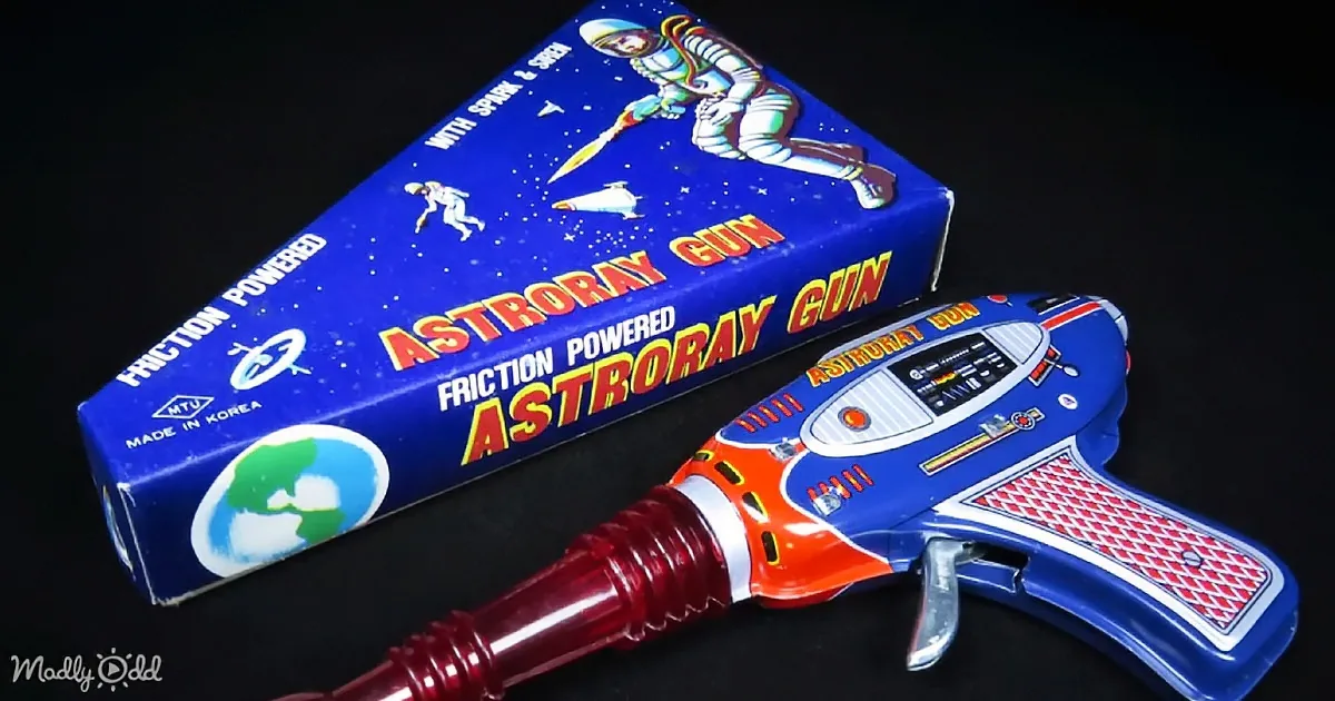 A vintage toy "Astro Ray Gun" with a blue box featuring astronauts and space imagery.