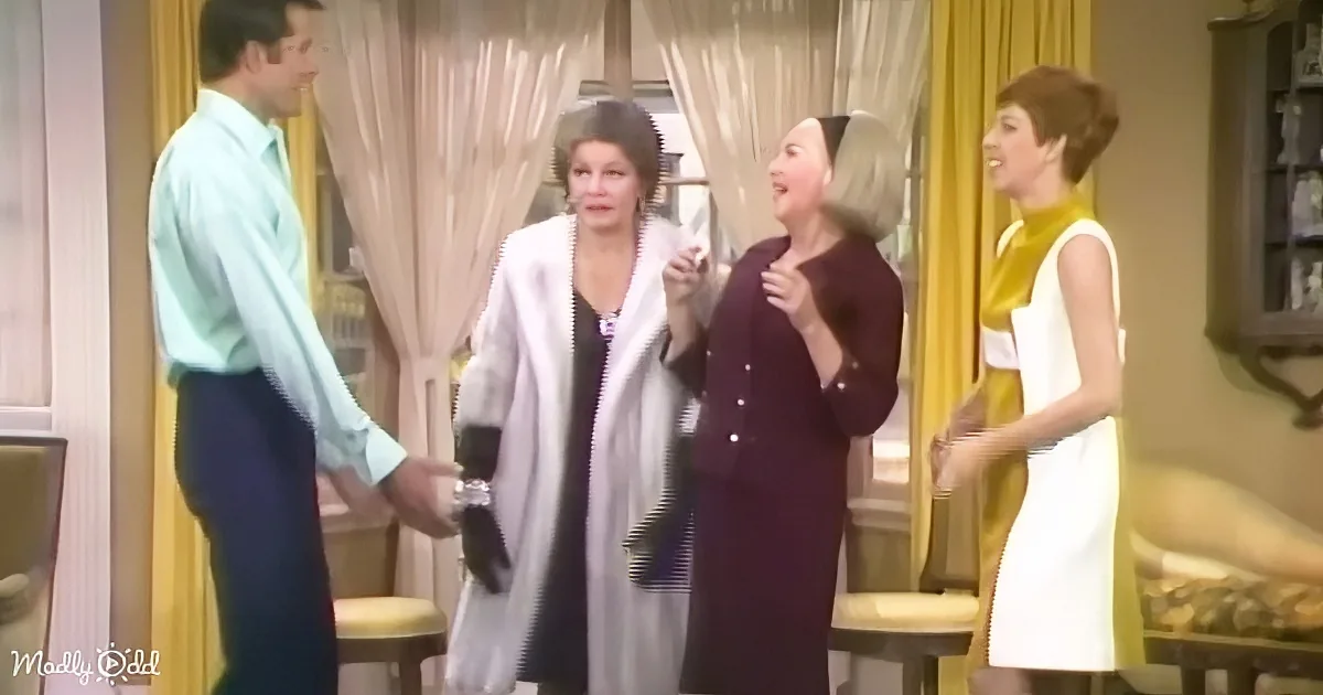 A man in a light green shirt is shaking hands with a woman in a white coat, while another woman in a purple suit and a...