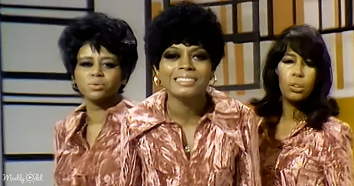 Three women in matching pink metallic shirts stand together, smiling and posing.