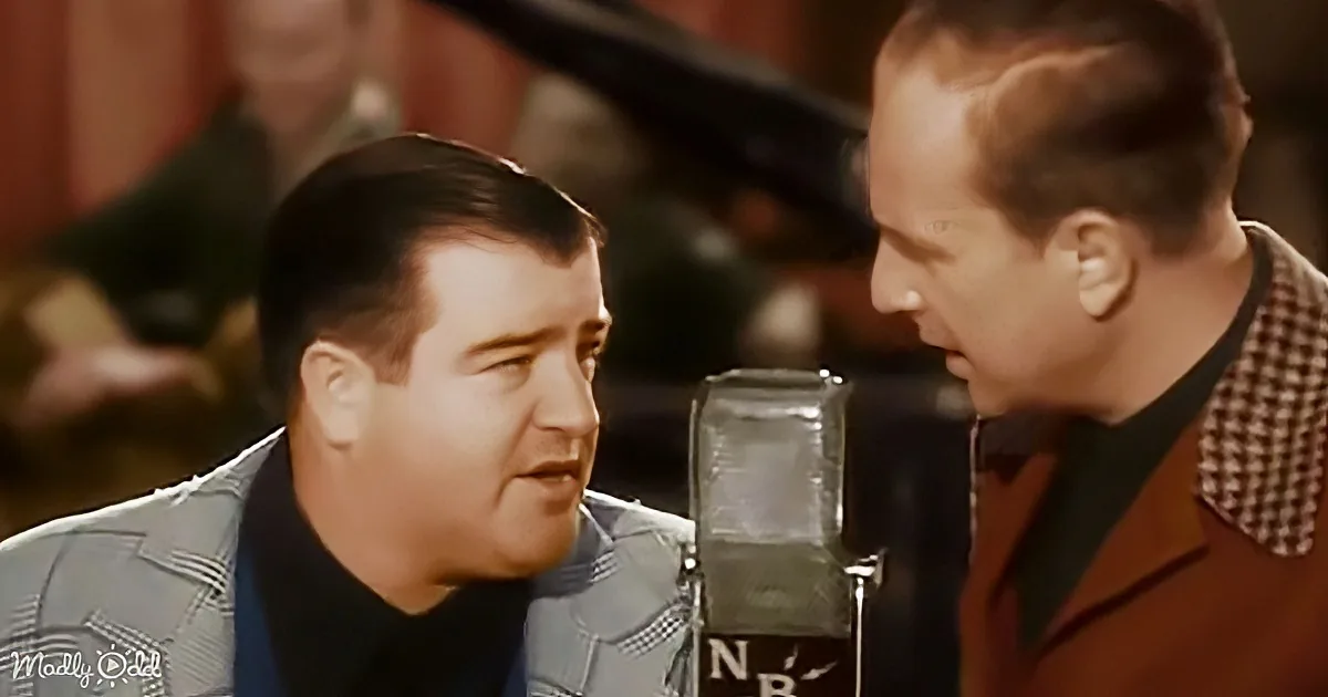 Two men in suits are singing into a microphone, one wearing a checkered pattern.