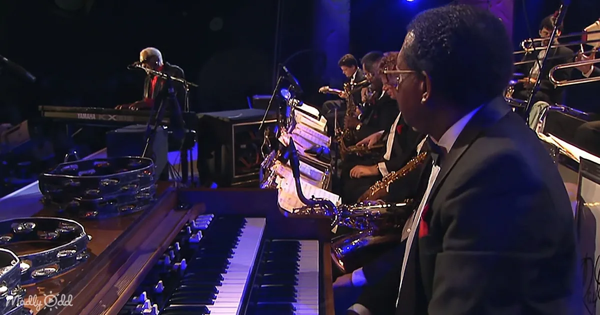 A musician plays a keyboard in a live performance setting with other musicians and instruments.