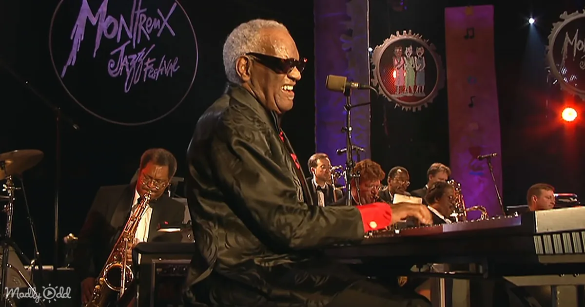 A smiling man in sunglasses plays piano at Montreux Jazz Festival, surrounded by musicians.