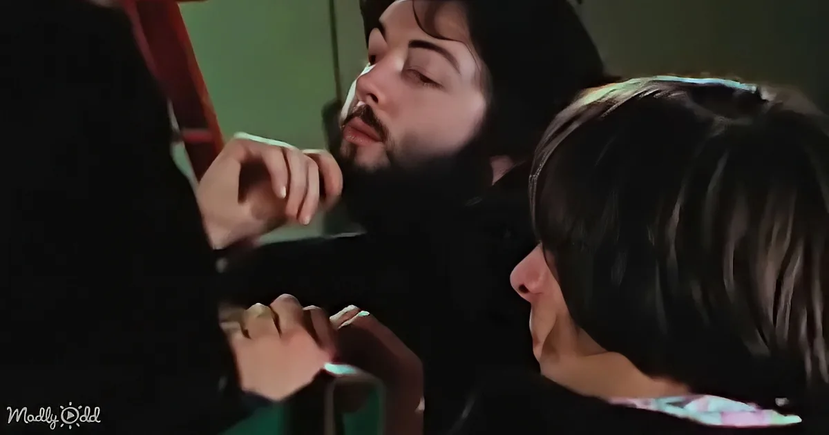 A man with closed eyes and a beard is leaning forward, appearing to be in a relaxed or possibly unconscious state.
