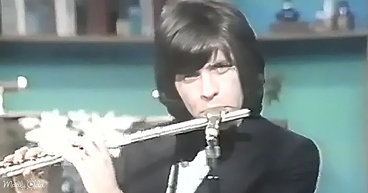 A person with dark hair is playing a flute in front of a pool.