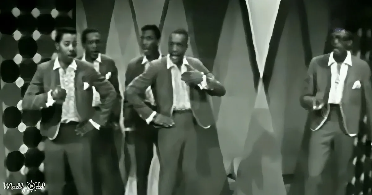 A group of men in suits and ties perform a synchronized dance routine on stage.