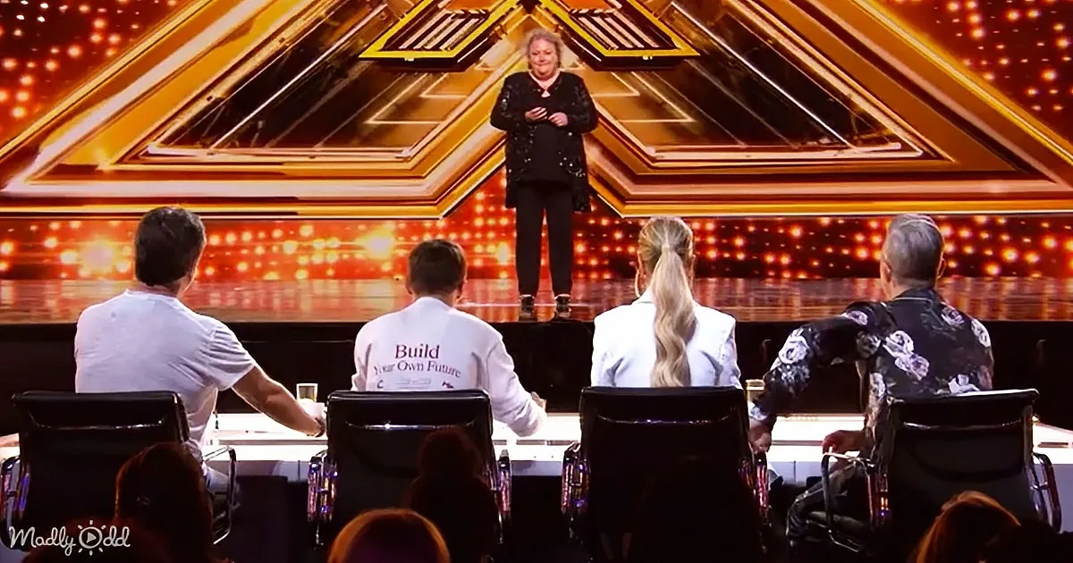 A woman stands on stage, facing judges seated at a table with a "Build Your Own Future" shirt.