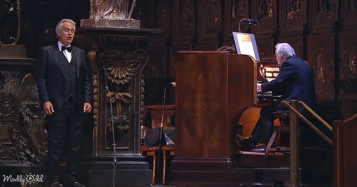 A man in a tuxedo sings on stage, accompanied by a pianist playing a grand piano.