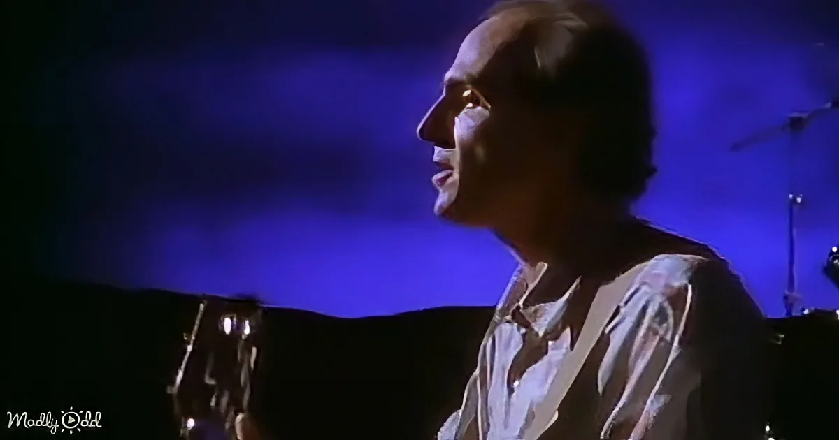 A person singing passionately while holding a guitar, illuminated by blue stage lighting.