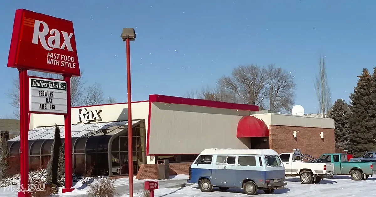 A vintage Rax fast food restaurant with a red sign, retro van, and snow-covered ground.