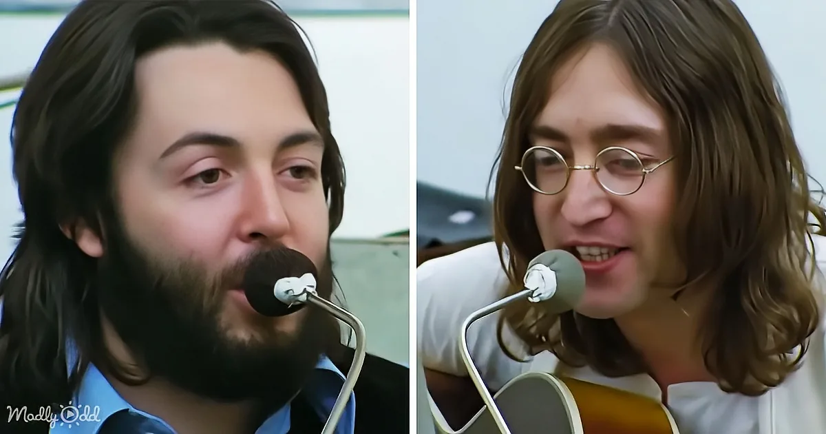 A man with long hair and a beard sings into a microphone, next to another man with long hair and glasses playing a guitar.