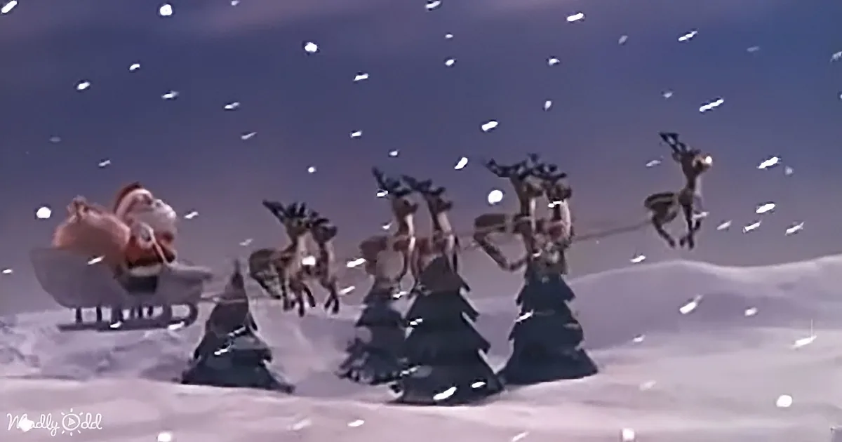 Santa in sleigh pulled by reindeer, snowy landscape, falling snowflakes.