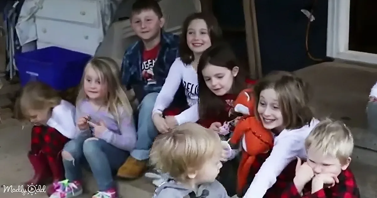 Children are gathered on a porch, some smiling, others focused on toys, creating a lively and cheerful scene.