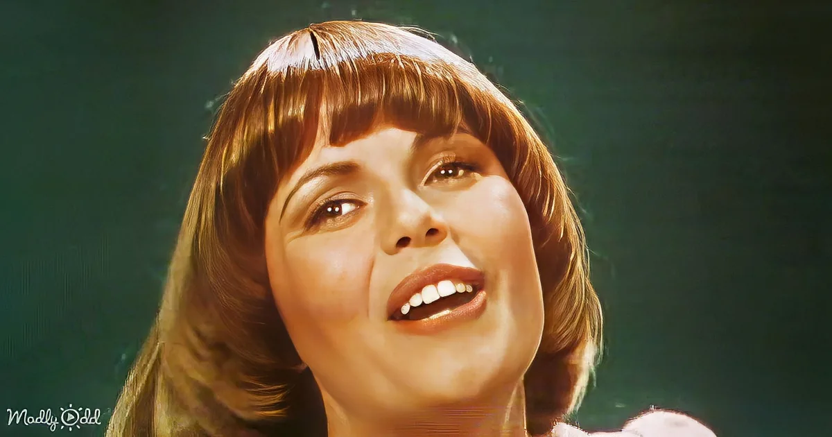 A person with short, wavy brown hair and bangs, looking upwards with a slight smile.