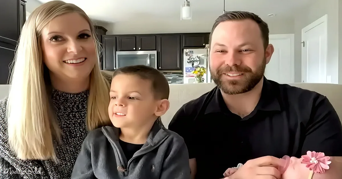 A family of three, a woman, a man, and a child, are sitting together in a kitchen, smiling.