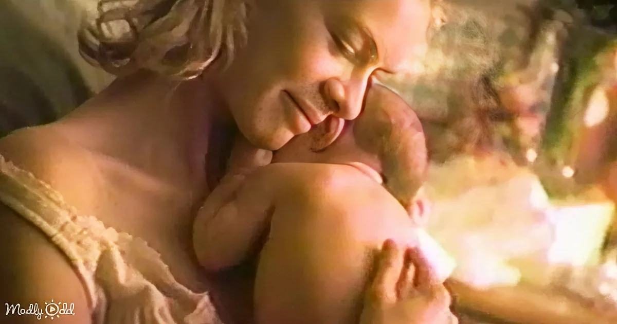 A woman is tenderly holding and kissing a baby, both appearing serene and affectionate.
