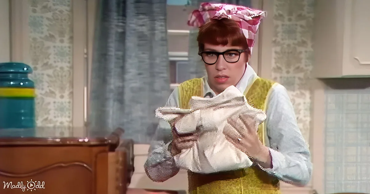A person wearing a checkered hat and glasses holds a flour bag in a kitchen setting.
