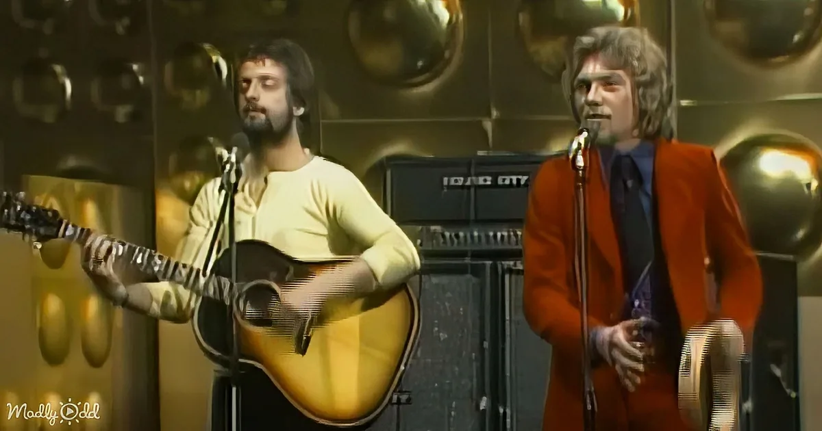 A man in a yellow shirt plays guitar while another in a red suit sings into a microphone.