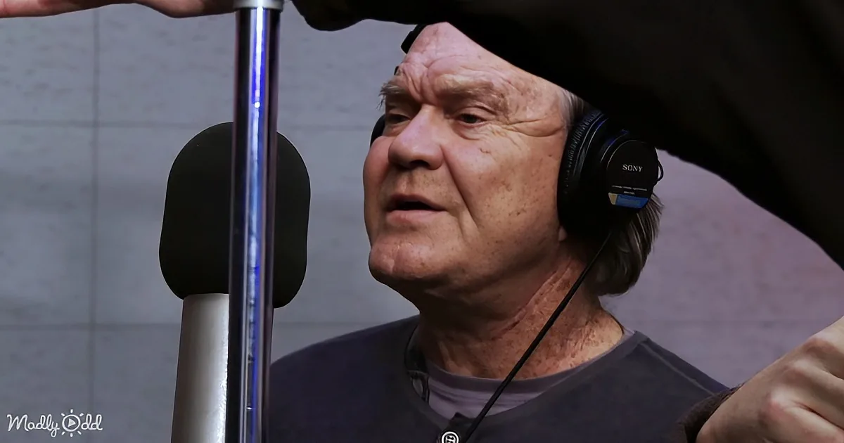 An older man wearing headphones and a microphone, seemingly in a recording studio.