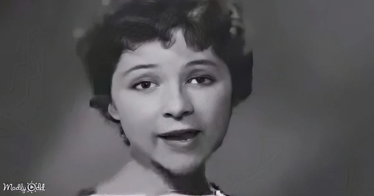 A woman with short, dark hair and a neutral expression is shown in a black-and-white portrait.