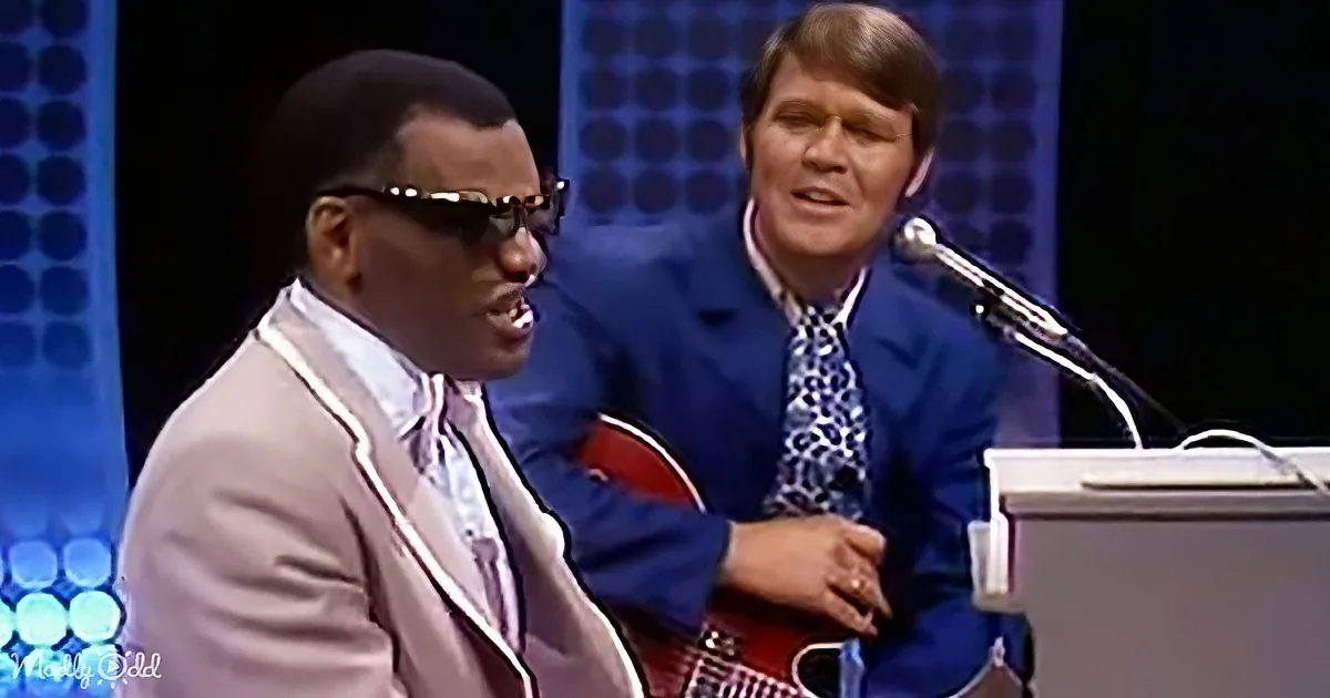 A man in a suit sings passionately, accompanied by another man playing a guitar.