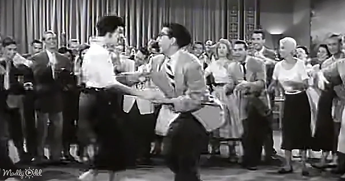 A man and woman are dancing in front of a crowd at a social event.
