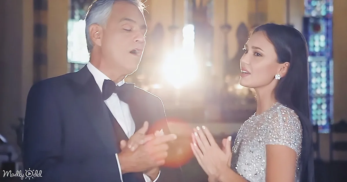 A man in a tuxedo and a woman in a sequined dress are dancing in a warmly lit room.