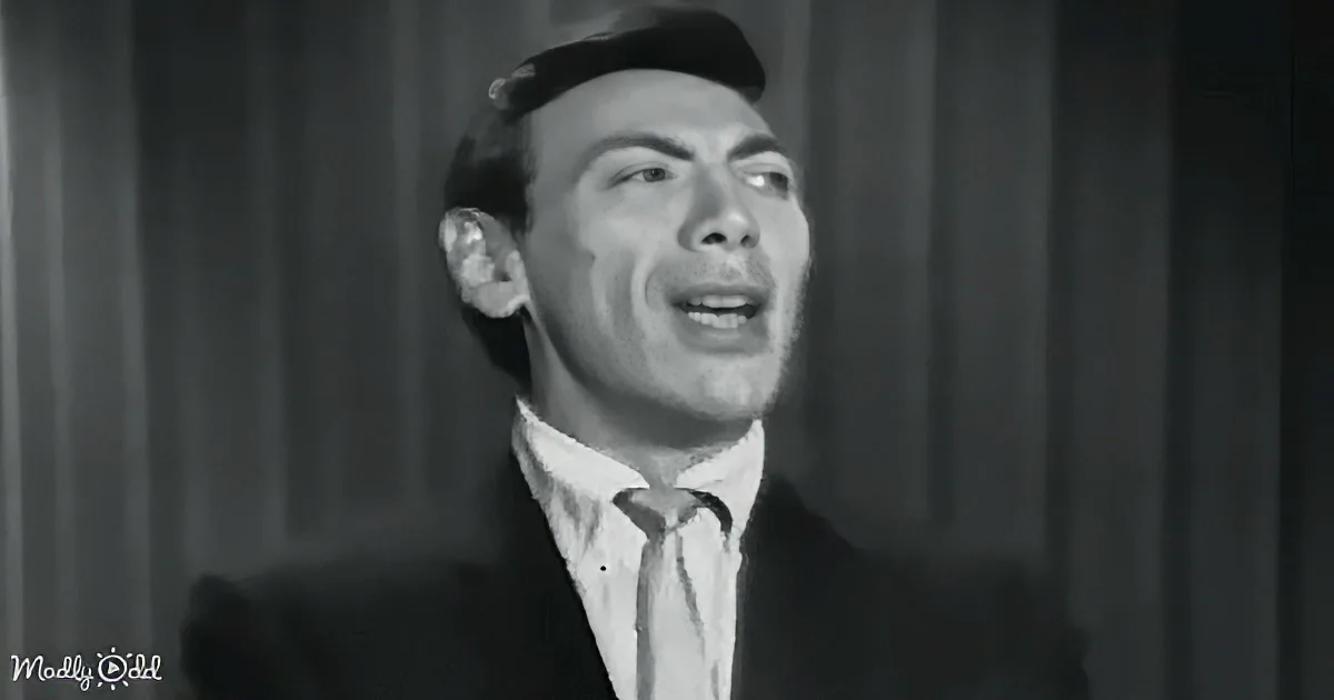 A man in a suit and tie, smiling widely, with a dark background.