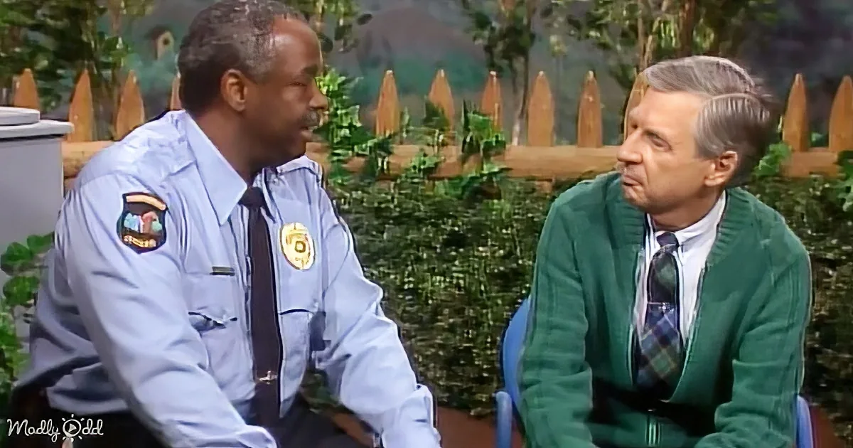 A man in a police uniform is talking to another man in a green sweater and tie.