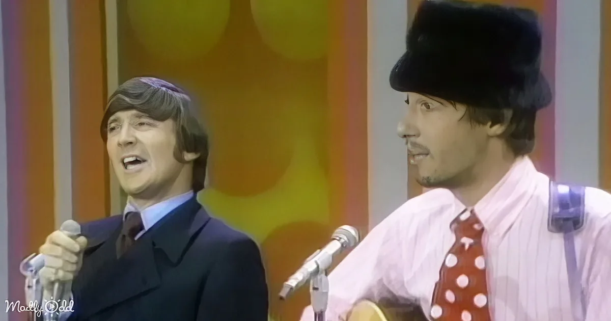 A man in a suit sings into a microphone while another man in a fur hat plays guitar.