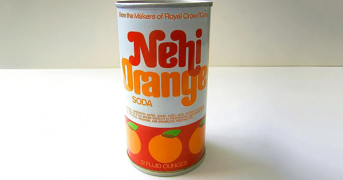 A can of Nehi Orange Soda, 12 fluid ounces, with orange and green fruit design, sits on a white surface.
