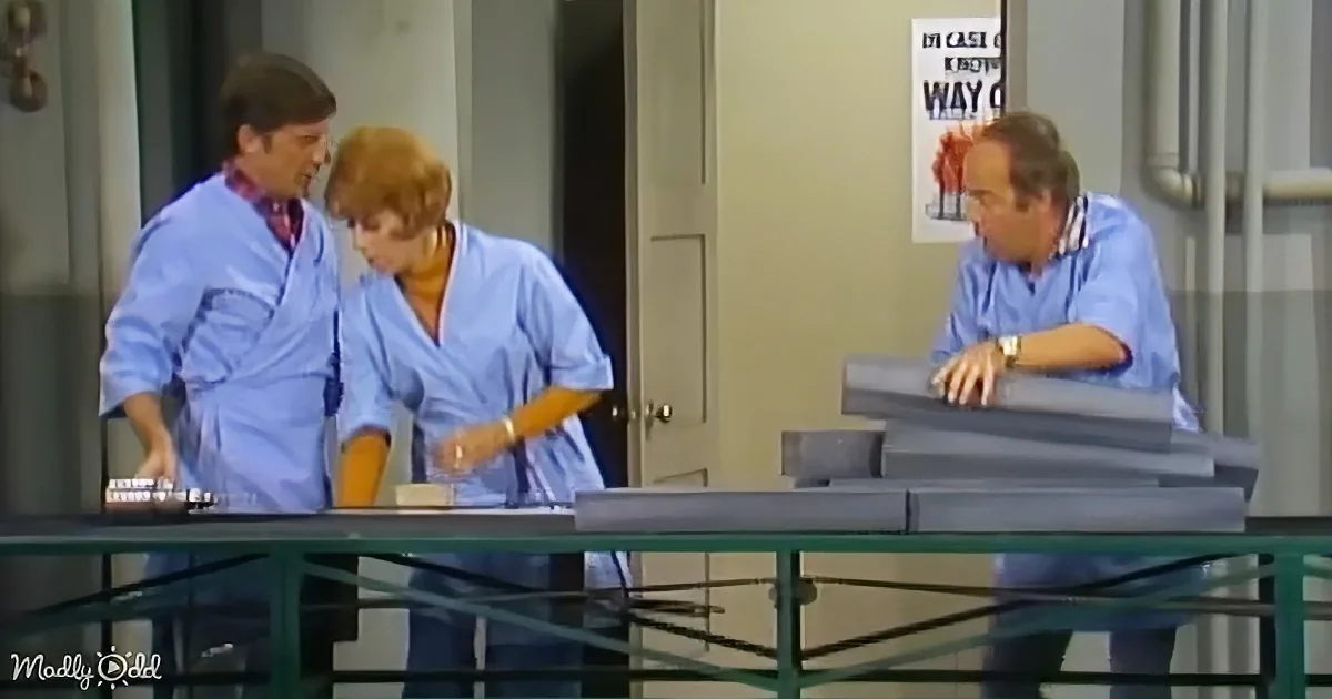 Three individuals in blue scrubs are gathered around a table, seemingly engaged in a discussion or examination.