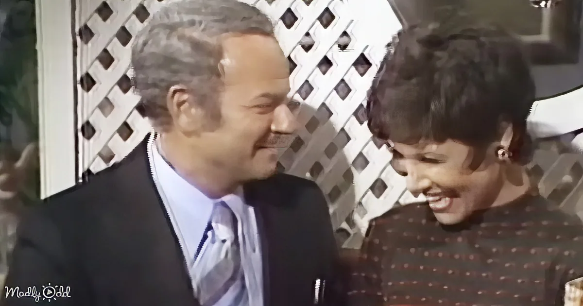 A man in a suit and tie is smiling at a young boy with a striped shirt, both appear happy.