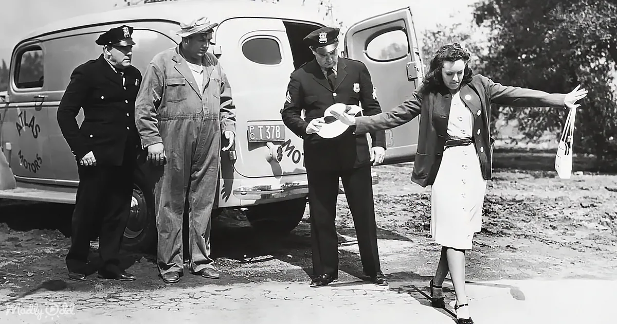 A woman in a dress is being escorted by two police officers near a vintage car.