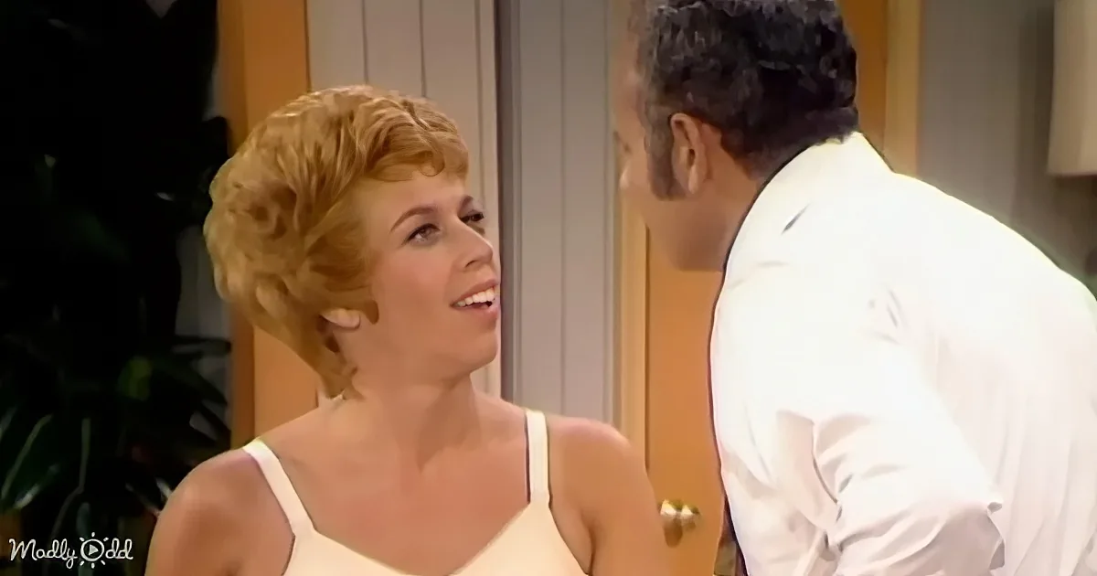 A woman with short blonde hair in a white dress smiles at a man in a white suit.