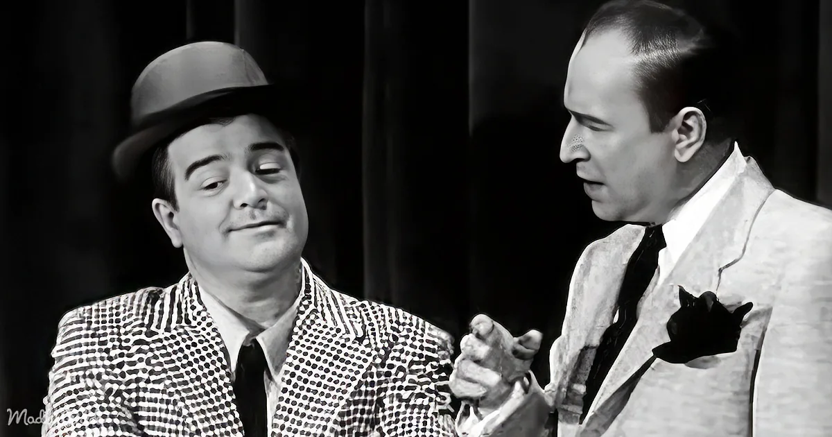 A man in a polka-dot suit and bowler hat is engaged in conversation with another man in a white suit and black tie.