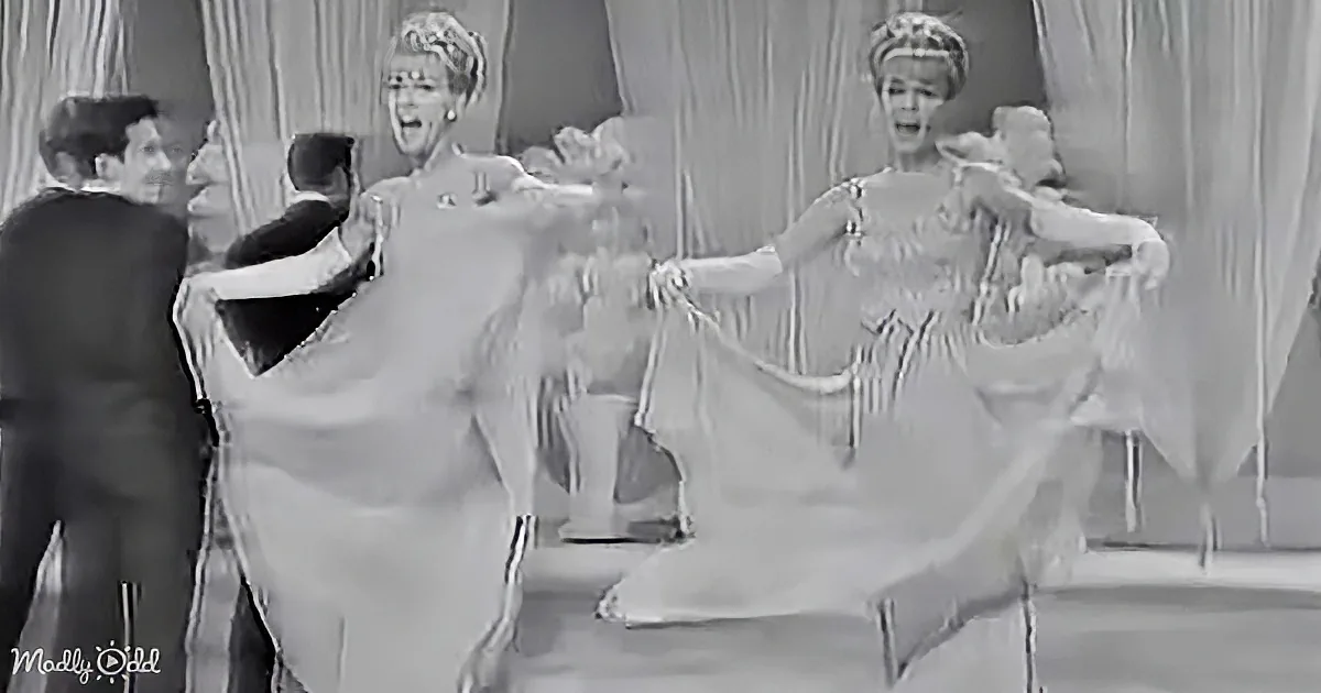A woman in a flowing dress is dancing energetically on stage, surrounded by other performers.